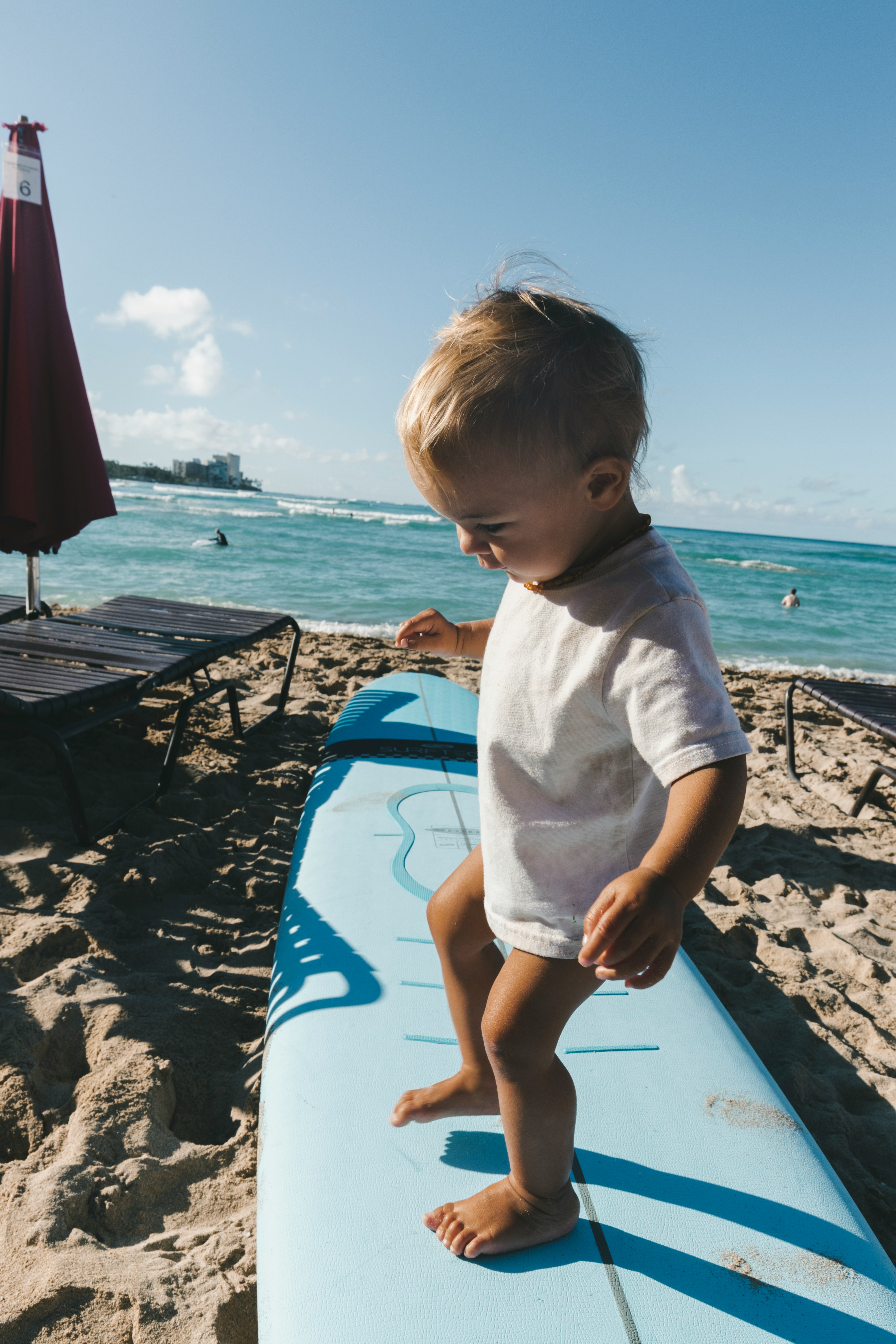 Surf coach guiding a student paddling on a longboard in calm water